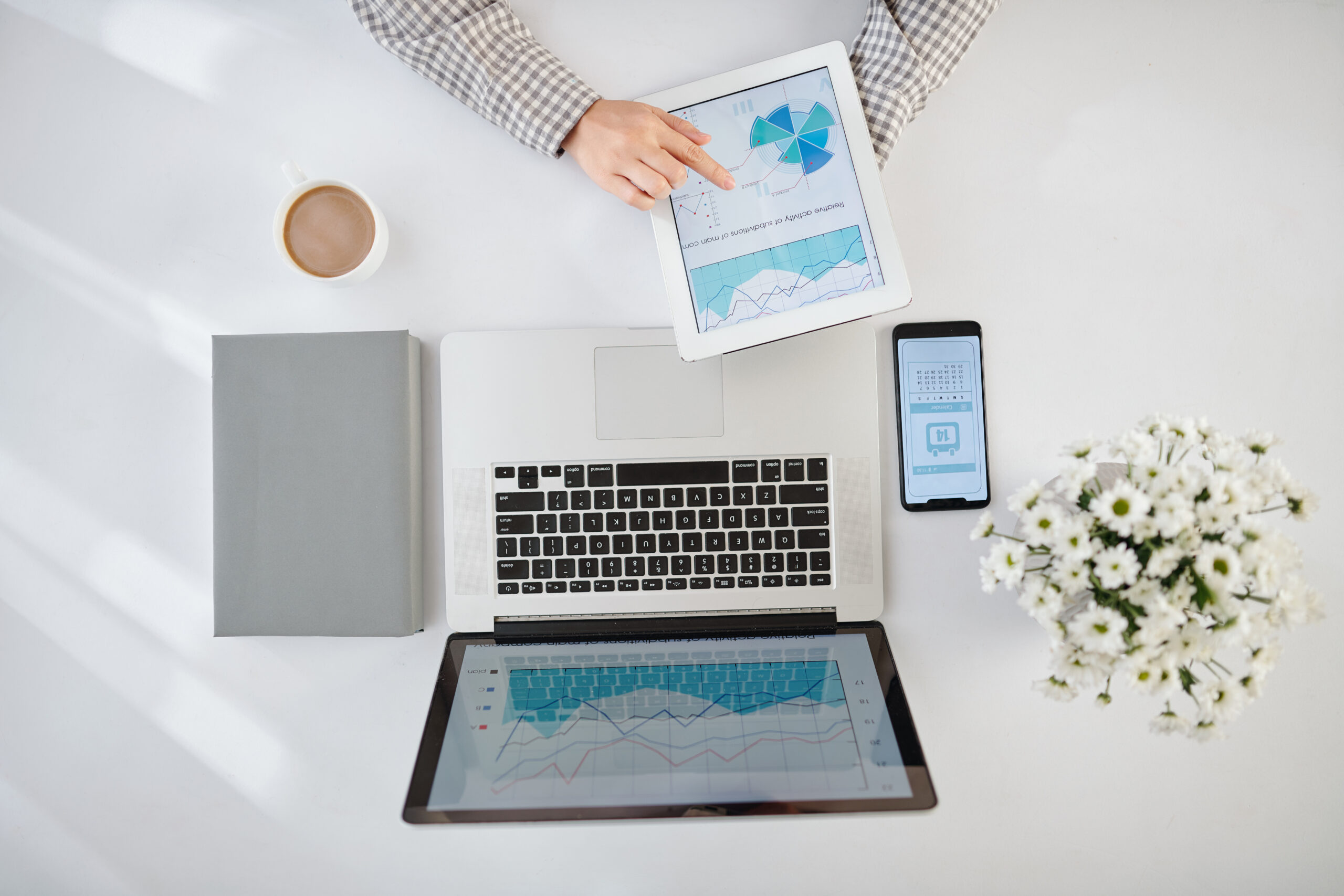 Businesswoman analyzing statistics in financial report on laptop and tablet computer and checking calendar on smartphone screen, view from the top